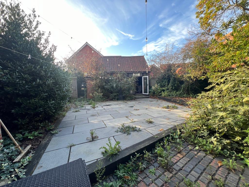 Lot: 15 - A CHARMING AND CHARACTERFUL COTTAGE LOCATED IN THE HISTORIC VILLAGE OF ST. OSYTH - Paved rear garden leading to outbuilding
